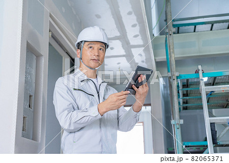 建築現場でタブレットを見ながら現場確認をする現場監督 建築現場でタブレットを見ながら現場確認をする現場監督 82065371