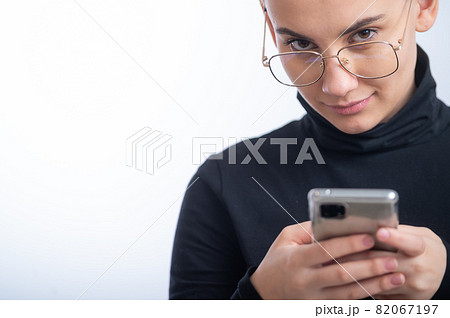 Young caucasian woman with short hair uses a smartphone on a white background. Young caucasian woman with short hair uses a smartphone on a white background. 82067197