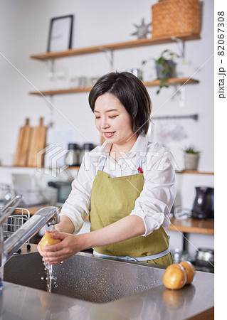 キッチンでじゃがいもを洗うエプロン姿の若い女性 キッチンでじゃがいもを洗うエプロン姿の若い女性 82067308