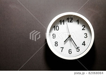 Modern white Wall Clock with black time pointer off center on black background. Shadows on the Clock Face. Concept Clock design with copy space for your own text. Business Clock show the day time 82068064