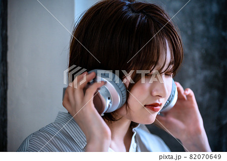 ヘッドフォンで音楽を聴く若い女性 82070649
