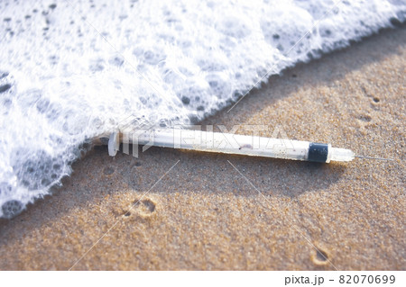 Medical syringe waste and foaming wave on the beach,Infectious wastes management concept Medical syringe waste and foaming wave on the beach,Infectious wastes management concept 82070699