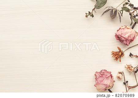 白木の木目の背景のピンクのバラのドライフラワーの飾りの写真素材 0709