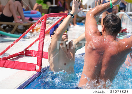 Young men playing water polo and scoring goal in swimming pool 82073323