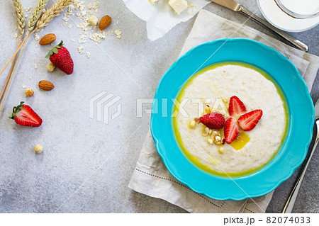 Healthy breakfast. Porridge of oatmeal with nuts and fresh strawberries on stone or slate background. The concept of nutrition health. Copy space, top view flat lay background. Healthy breakfast. Porridge of oatmeal with nuts and fresh strawberries on stone or slate background. The concept of nutrition health. Copy space, top view flat lay background. 82074033