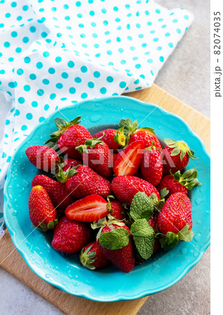 Berries of fresh strawberries in a blue ceramic plate on a gray stone or slate background. The concept of nutrition for superfoods and health or detoxification. Berries of fresh strawberries in a blue ceramic plate on a gray stone or slate background. The concept of nutrition for superfoods and health or detoxification. 82074035