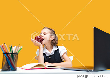 Little schoolgirl eating an apple while change at online lesson. Distance education  82074150