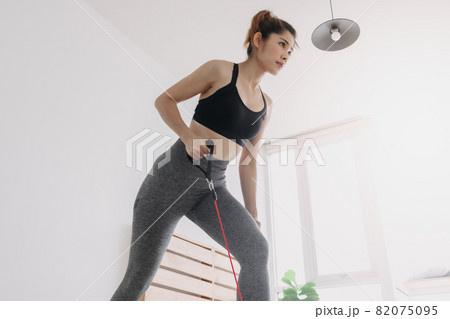 Woman do Resistance Band Crank the Mower workout in her bedroom. Woman do Resistance Band Crank the Mower workout in her bedroom. 82075095