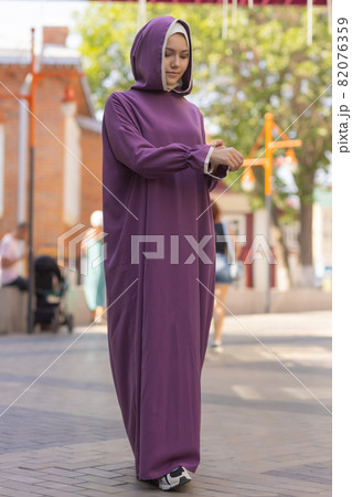 Islamic beautiful woman in a Muslim dress standing on a summer park street background forest autumn trees.world hijab day. Islamic beautiful woman in a Muslim dress standing on a summer park street background forest autumn trees.world hijab day. 82076359