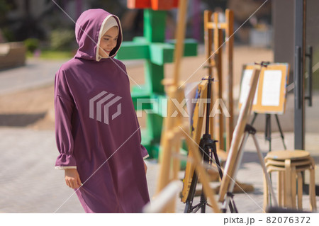 Islamic beautiful woman in a Muslim dress standing on a summer park street background forest autumn trees.world hijab day. Islamic beautiful woman in a Muslim dress standing on a summer park street background forest autumn trees.world hijab day. 82076372