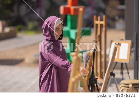 Islamic beautiful woman in a Muslim dress standing on a summer park street background forest autumn trees.world hijab day. Islamic beautiful woman in a Muslim dress standing on a summer park street background forest autumn trees.world hijab day. 82076373
