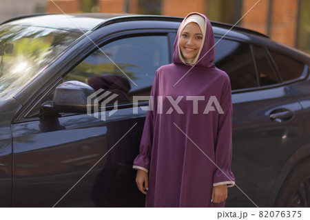 Islamic beautiful woman in a Muslim dress standing on a summer park street background forest autumn trees.world hijab day. Islamic beautiful woman in a Muslim dress standing on a summer park street background forest autumn trees.world hijab day. 82076375