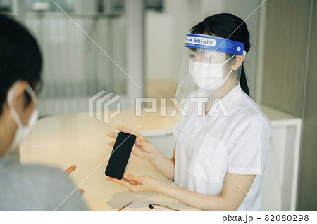 病院の受付にいる女性（スマホ・案内） 82080298