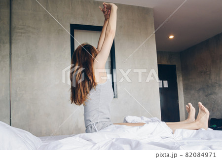 Portrait of young Asian woman raised her hands and stretching in bed after her waking up in the morning. Conceptual of woman lifestyle. Portrait of young Asian woman raised her hands and stretching in bed after her waking up in the morning. Conceptual of woman lifestyle. 82084971