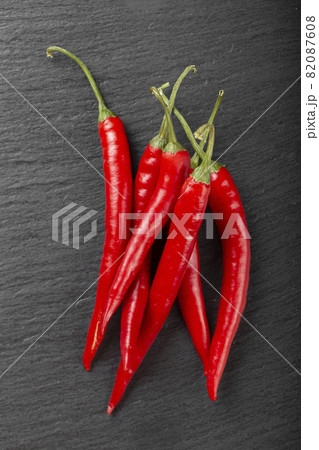 Pods of red chili peppers on a dark background Pods of red chili peppers on a dark background 82087608