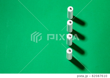 White AA batteries on a green background. Space for text. White AA batteries on a green background. Space for text. 82087610