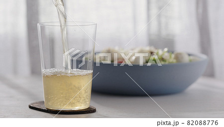 closeup pour ginger beer in a tumbler glass on oak table with blue bowl on background closeup pour ginger beer in a tumbler glass on oak table with blue bowl on background 82088776
