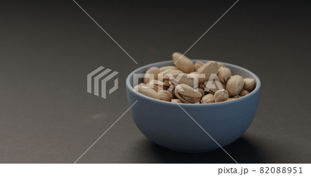 salted pistachios in blue bowl on black background 82088951