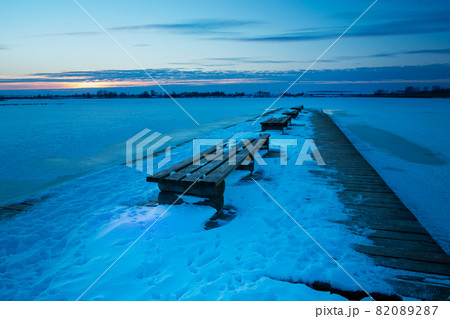 Wooden pier with benches and a snow-covered lake 82089287