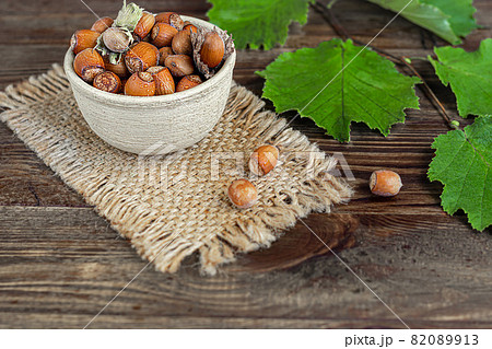 Hazelnuts on a wooden background with green leaves. Contains beneficial vitamins and minerals. 82089913