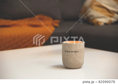 Concrete candlestick on table in living room next to sofa with pillows and blanket. Autumn comfort hyggelig at home Concrete candlestick on table in living room next to sofa with pillows and blanket. Autumn comfort hyggelig at home 82090076
