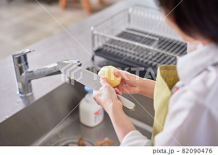 キッチンでじゃがいもの芽を取り除くエプロン姿の若い女性 キッチンでじゃがいもの芽を取り除くエプロン姿の若い女性 82090476