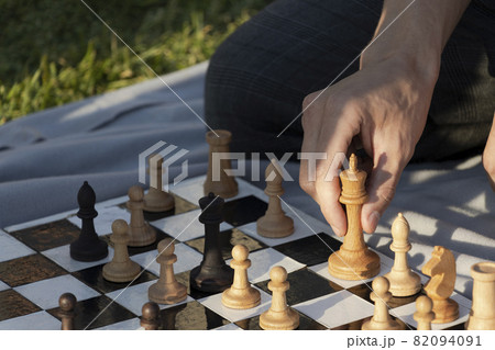 Young man making a move by wooden chess piece. Concept of the outdoor activity. 82094091