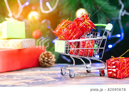 Mini shopping basket with red christmas gifts on the background of the christmas tree 82095678