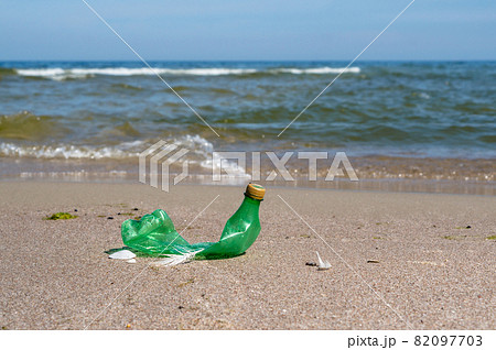 Garbage on the beach. Plastic on the beach. Pollution of the coast with plastic bottles. Green empty bottle. 82097703