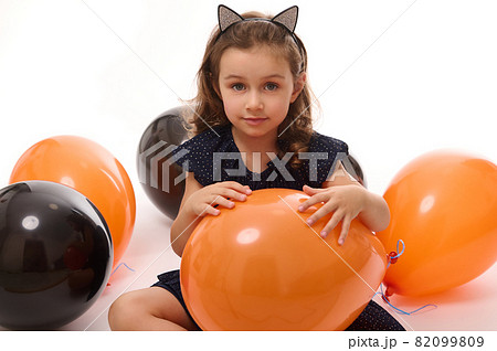 4 y.o adorable pretty little girl in witch costume plays with black and orange balloons isolated on white background. Concept of a happy child having fun at Traditional seasonal event, Halloween party 4 y.o adorable pretty little girl in witch costume plays with black and orange balloons isolated on white background. Concept of a happy child having fun at Traditional seasonal event, Halloween party 82099809