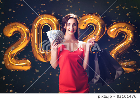 Woman with dollars and purchases. New Year shopping. Black Friday. 2022 balloons. Christmas sales Woman with dollars and purchases. New Year shopping. Black Friday. 2022 balloons. Christmas sales 82101476
