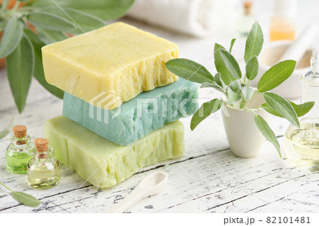 Homemade natural organic soap bars, bottles of essential oil and fresh green sage leaves on white table. Homemade natural organic soap bars, bottles of essential oil and fresh green sage leaves on white table. 82101481