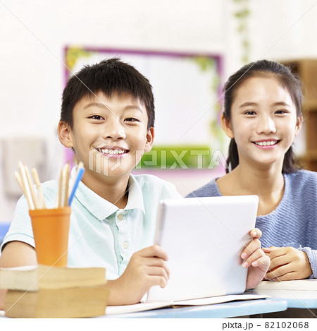 portrait of two happy asian primary school students looking at camera smiling 82102068