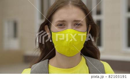 Young girl schoolgirl smiling in a protective mask, coronavirus pandemic, covid 19, safe walking around the city, helps from infections and dust, air filtration, keep healthy people safe, concept 82103191