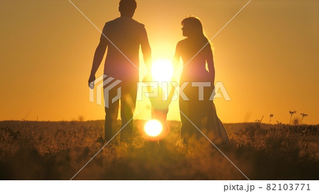 A small child walks with mom and dad at a bright sunset in the sky. Meet the sunrise with your family while traveling. Go hiking with your mother and father. Kid and loving parents walk in the park A small child walks with mom and dad at a bright sunset in the sky. Meet the sunrise with your family while traveling. Go hiking with your mother and father. Kid and loving parents walk in the park 82103771