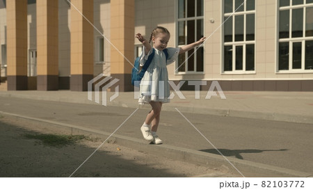 Happy little girl playing in the schoolyard, a little kid with a backpack, a child's school bag on the baby's shoulders, a fun child's primary education, a childhood dream, a fun school life Happy little girl playing in the schoolyard, a little kid with a backpack, a child's school bag on the baby's shoulders, a fun child's primary education, a childhood dream, a fun school life 82103772