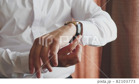 A man looks at the dial of the clock on his hand, to check the time, to be late for work in the morning, the businessman is punctual, the business plan is on time A man looks at the dial of the clock on his hand, to check the time, to be late for work in the morning, the businessman is punctual, the business plan is on time 82103773