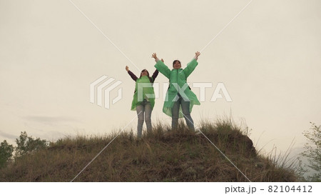 An adult girl climbs a mountain in the rain areas with backpacks, the women travelers have a healthy day of rest together, 4K, outdoor life, teamwork, a camping trip of people with backpacks, slow 82104412