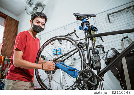 a mechanic in mask working tighten the bicycle axle with a wrench 82110548
