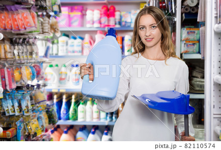 Young woman holding bottle of detergent and plastic scoop in household chemistry store Young woman holding bottle of detergent and plastic scoop in household chemistry store 82110574
