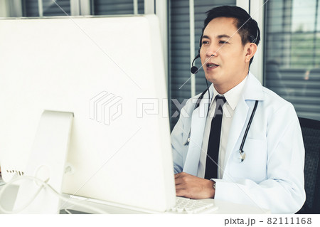 Doctor wearing headset talking actively on video call in a clinic or hospital . Doctor wearing headset talking actively on video call in a clinic or hospital . 82111168