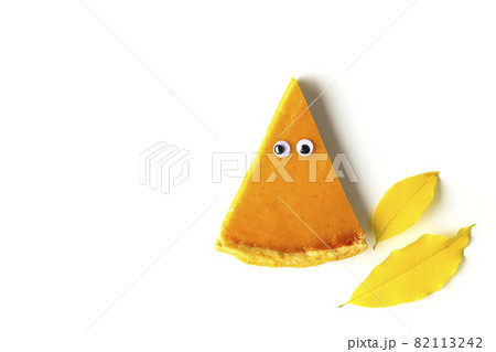 Slice of pumpkin pie in form of Halloween ghost with eyes on white isolated background. Festive creative food concept 82113242