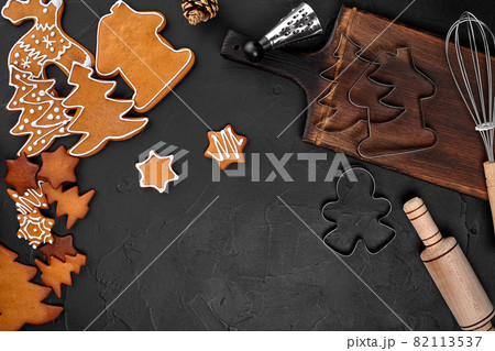 Christmas homemade gingerbread cookies, spices and cutting board on dark background with copy space for text top view. New year and christmas postcard 82113537