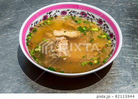 Hot clear soup of fresh pork rib seasoning with soy sauce and pepper. Pork bone soup in white bowl. Hot clear soup of fresh pork rib seasoning with soy sauce and pepper. Pork bone soup in white bowl. 82113944