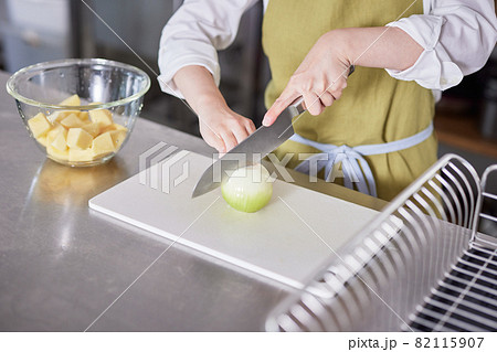 玉ねぎを包丁で切るエプロン姿の若い女性 玉ねぎを包丁で切るエプロン姿の若い女性 82115907
