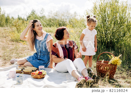 A grandmother and her two granddaughters have a picnic in nature, spend time together on weekends 82116024