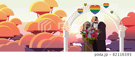 newlywed gay couple with flowers kissing near wedding arch transgender love LGBT community wedding newlywed gay couple with flowers kissing near wedding arch transgender love LGBT community wedding 82116393