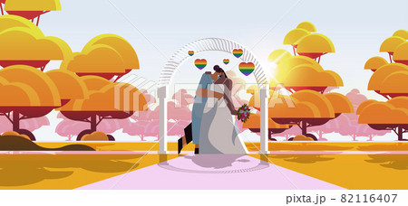 newlywed lesbian couple with flowers kissing near wedding arch transgender love LGBT community wedding celebration newlywed lesbian couple with flowers kissing near wedding arch transgender love LGBT community wedding celebration 82116407