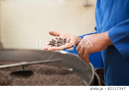Close-up of man holding roasted coffee beans 82117347