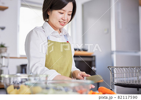 キッチンで料理をするエプロン姿の若い女性 キッチンで料理をするエプロン姿の若い女性 82117590